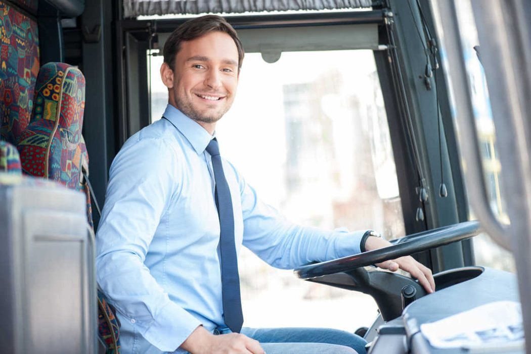 Autista sorridente alla guida di un autobus